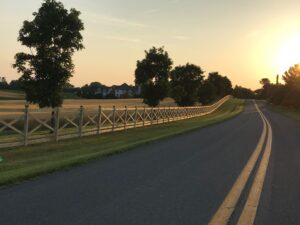 white fence along rural road in sunset